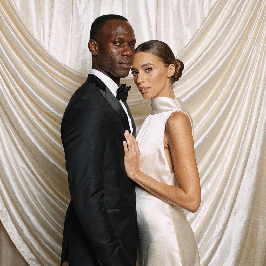 A bride and groom in the studio set against a draped ivory backdrop